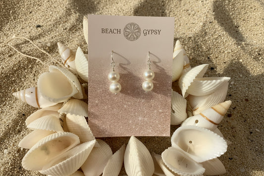 Pearl earrings on a 'Beach Gypsy' branded card with seashells in the background
