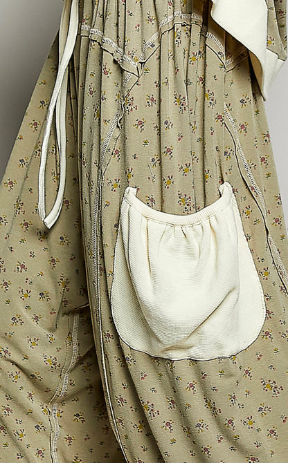 Close up of fabric on Woman wearing flowing sage colored ditzy flower print pants with cream patch pockets