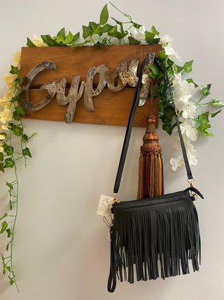 black fringe crossbody bag hanging from gypsy sign
