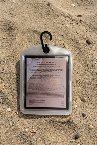 A reusable gel pouch with a black hook at the top, containing a pink and white instruction card