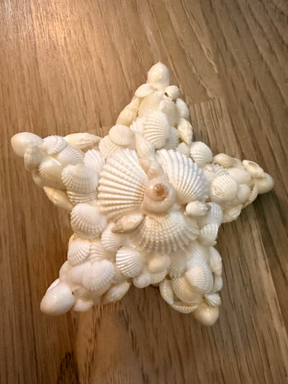 Star-shaped decorative item made of small shells on a wooden surface