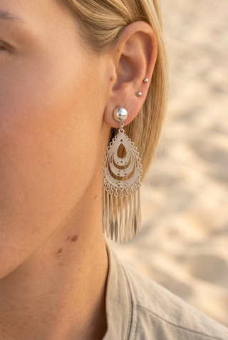 Close-up of a woman at the beach wearing Silver Filigree Teardrop Fringe Earrings with a pearl-style stud top