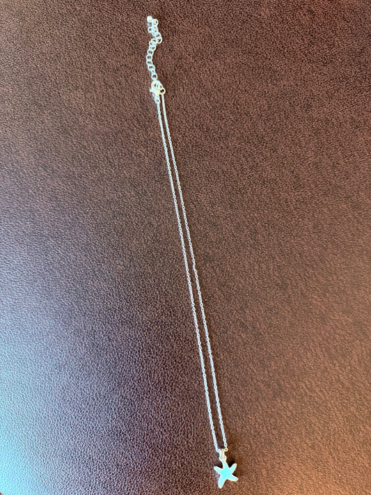 Silver necklace with a star pendant on a brown textured surface