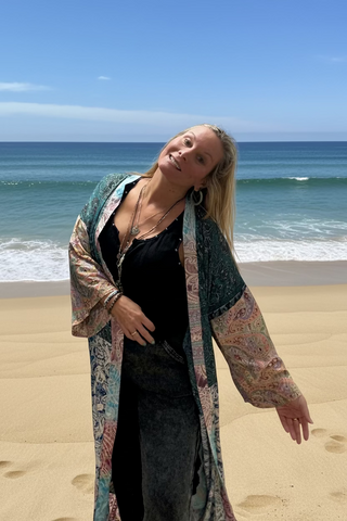 Woman wearing a patched patterned kimono standing on the beach. 