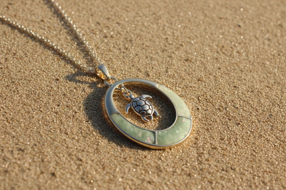 Gold pendant with turtle charm on a beach