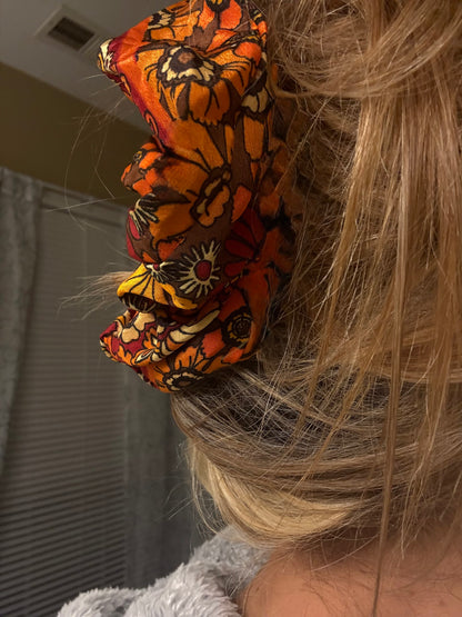 Close-up of a person wearing an orange and black patterned hair scrunchie