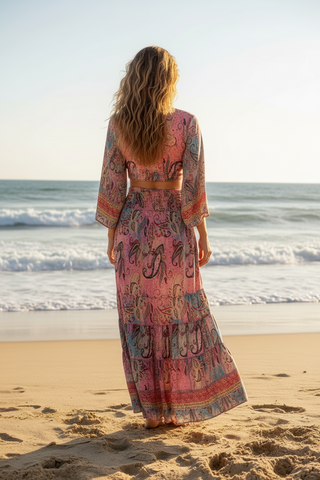 Back view of wrap silky top and ruched waist long flowy slimy skirt on a woman standing on a beach 