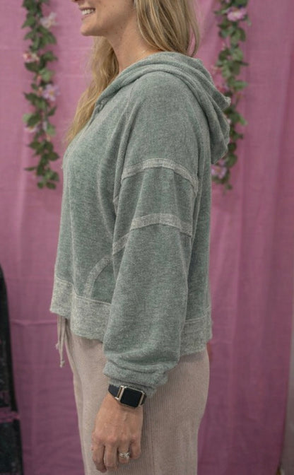 Person wearing a green hoodie with a pink background