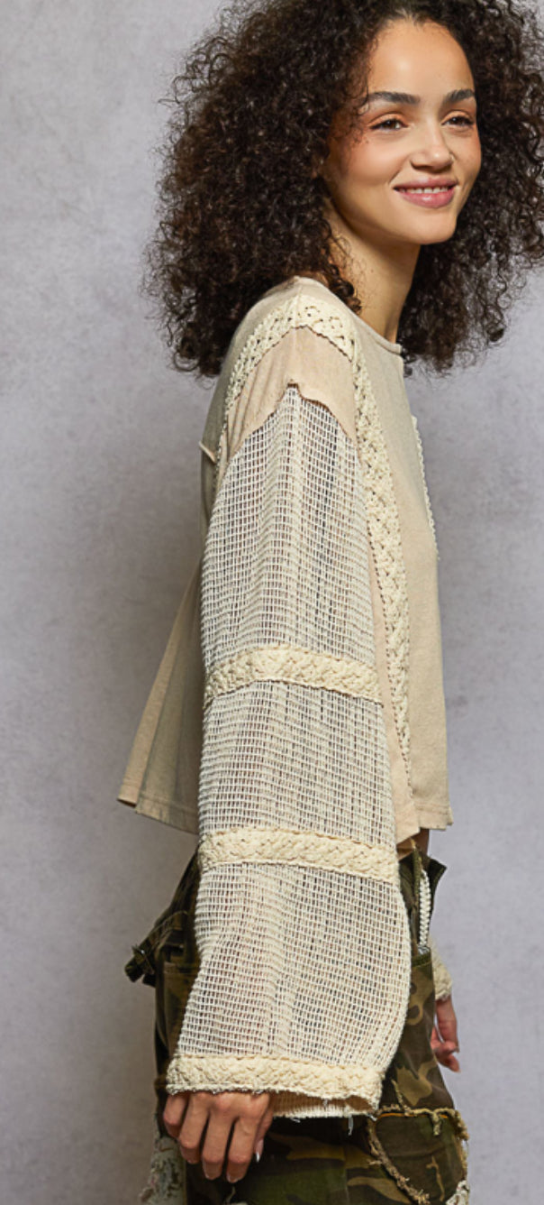 Woman wearing a beige lace top over a green dress against a gray background