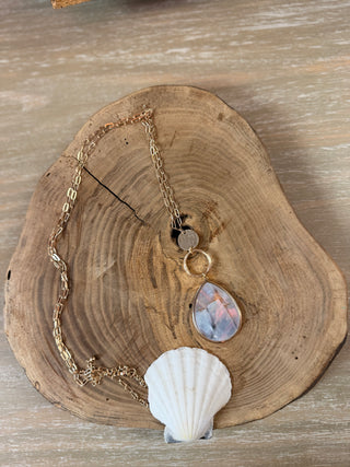 A gold chain necklace with a teardrop-shaped iridescent mother of Pearl shell pendant 