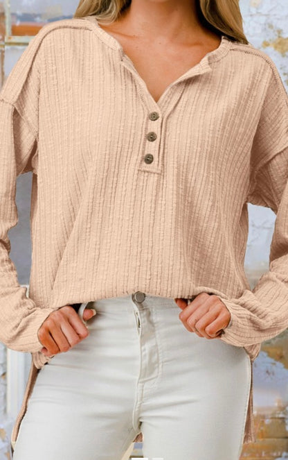Beige ribbed long-sleeve top worn by a person with a blurred background