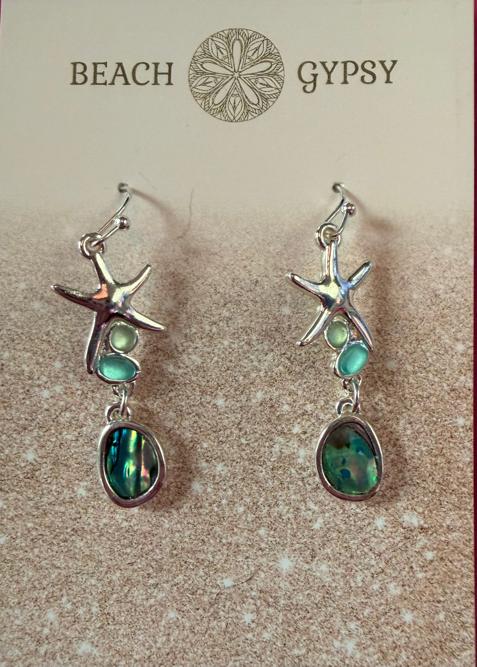 Starfish-shaped earrings with green stones on a 'Beach Gypsy' branded card.