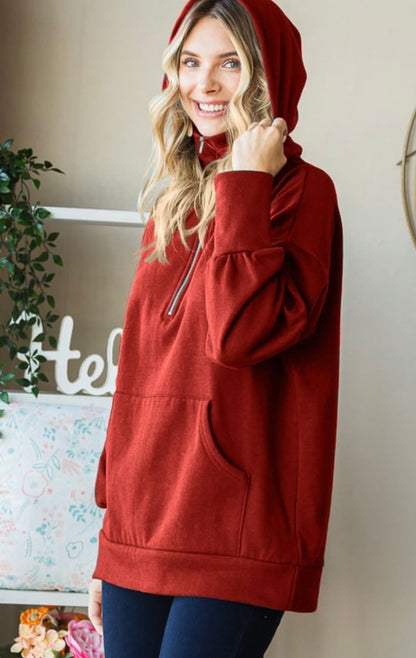 Woman wearing a red hoodie indoors with a neutral background