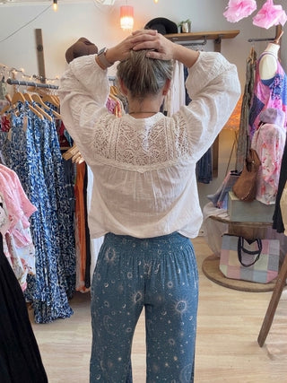 Back view of Woman looking up in a beach vibe shop wearing blue Cosmic Sky Harem Pants