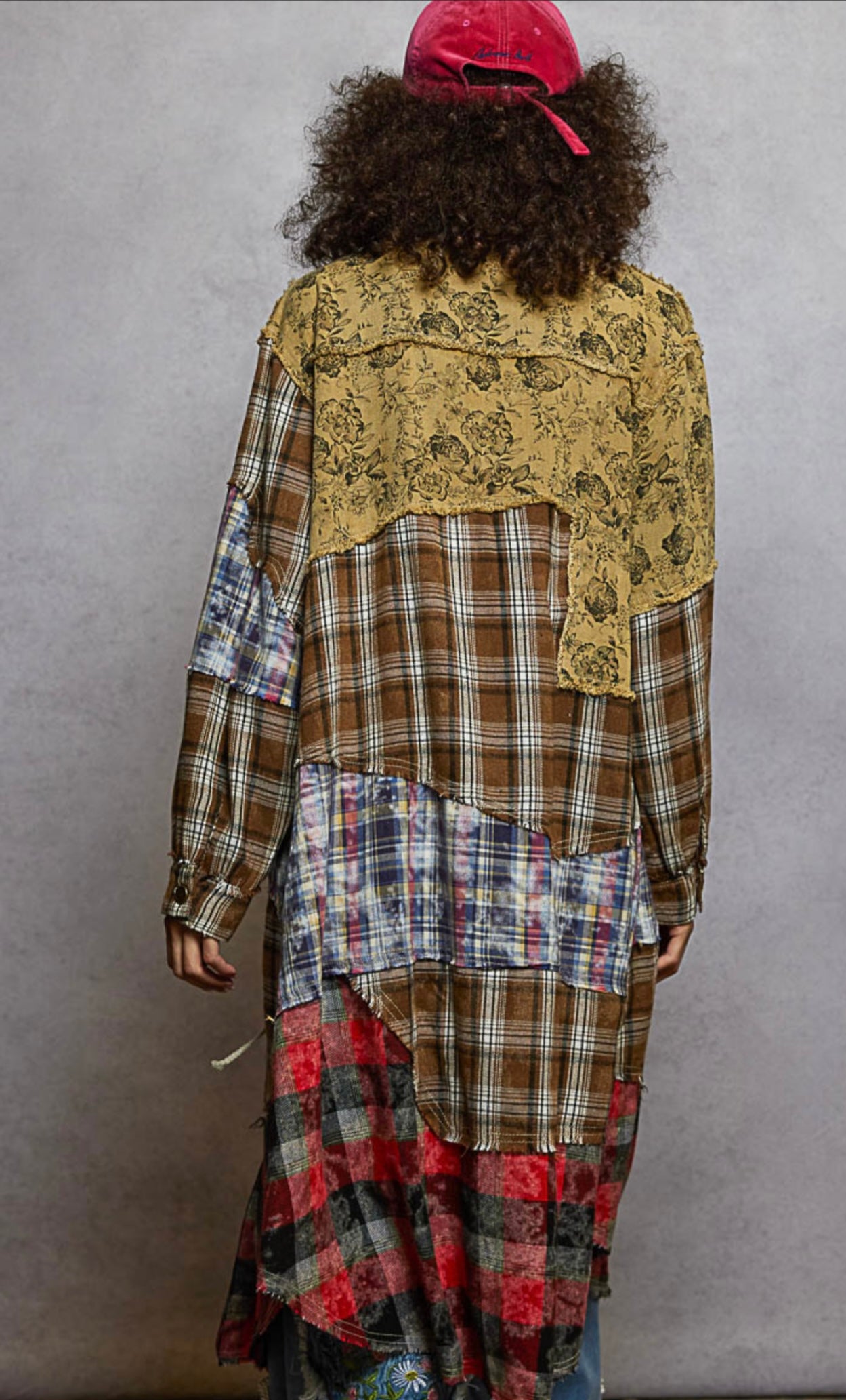 Person wearing a patchwork dress with a yellow lace top and plaid layers, standing against a plain background.