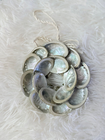 Decorative abalone shell ornament made of shell pieces on a white fluffy background