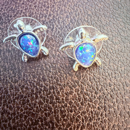 Turtle-shaped earrings with blue gemstones on a textured brown surface