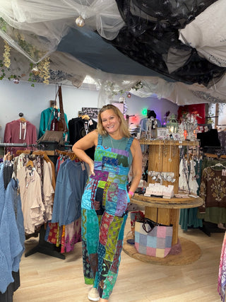 Woman wearing a colorful boho patchwork jumpsuit with wide legs, posing inside the Beach Gypsy boutique