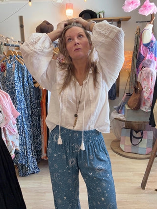 Woman looking up in a beach vibe shop wearing blue Cosmic Sky Harem Pants