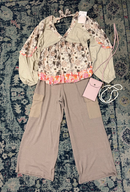 Fashion outfit with floral top and beige pants on a textured rug