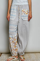 Person wearing light gray pants with floral patterns and a striped shirt against a neutral background.