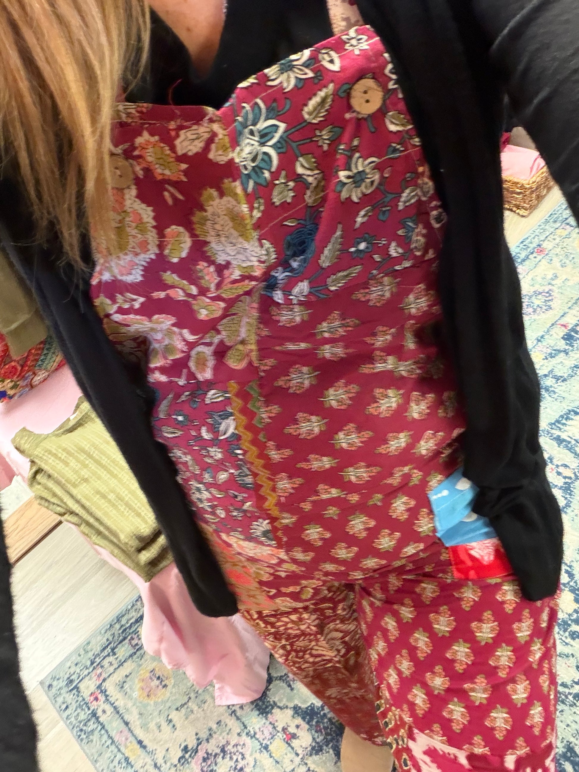 Person wearing a colorful floral-patterned overalls with a red base color.