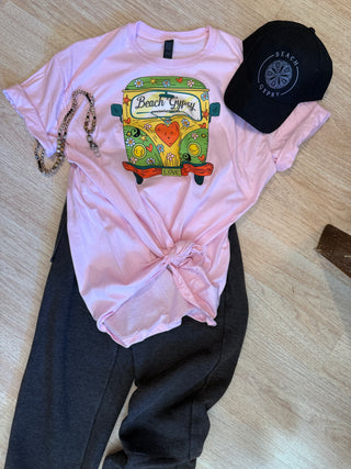 Pink t-shirt with 'Beach Gypsy' design, black cap, and necklace on a wooden surface