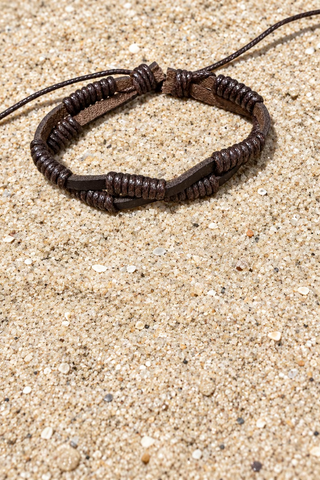 A dark brown leather bracelet with a textured, coiled wrap design