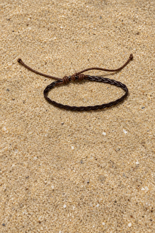 A dark brown braided cord bracelet with an adjustable sliding knot closure