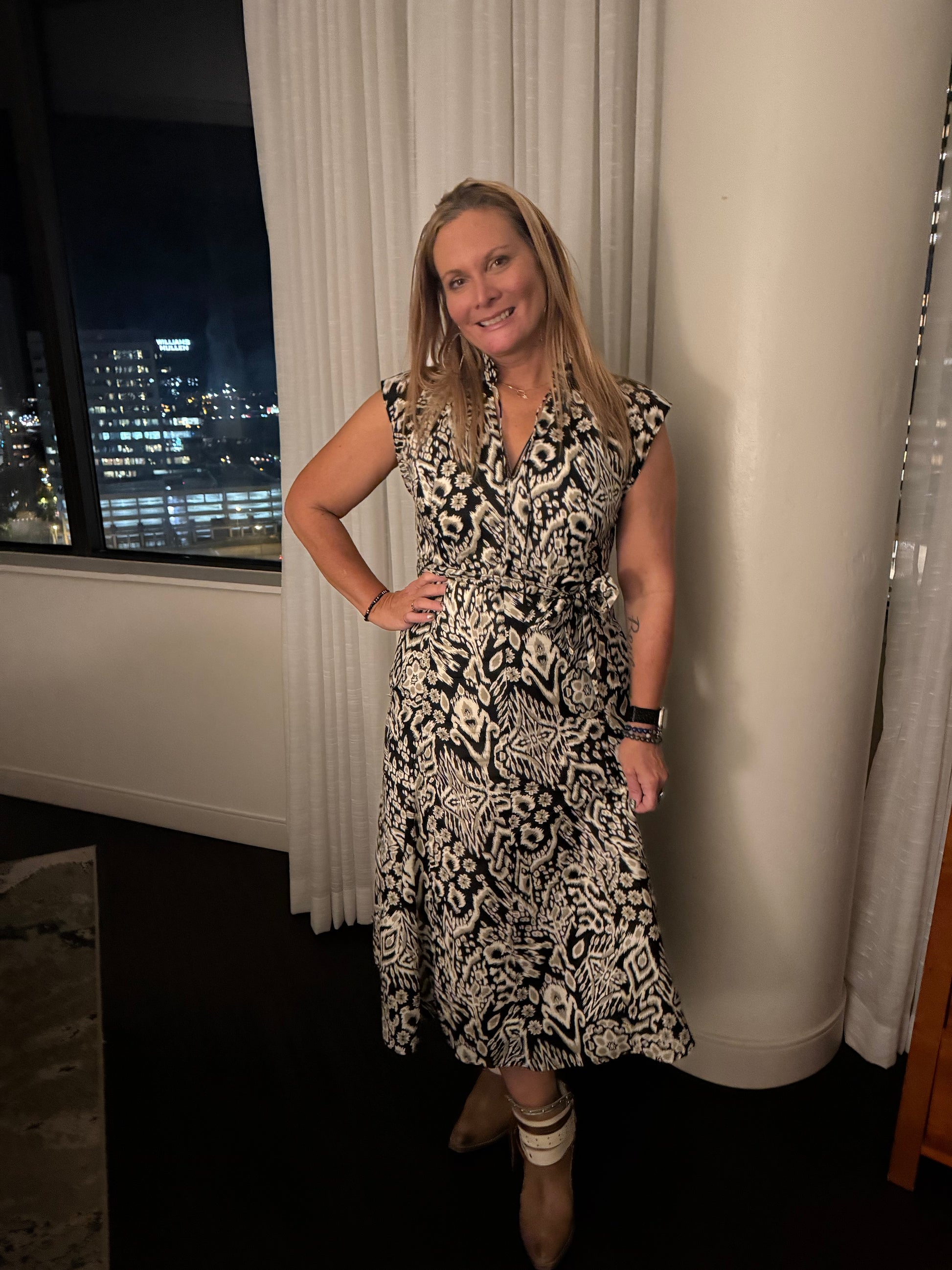 Woman wearing black and white patterned dress with cityscape in background 