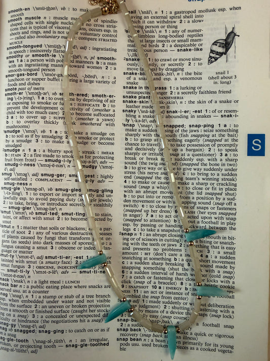 Teal and silver necklace on a dictionary page
