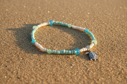 Beaded bracelet with a turtle charm on sand