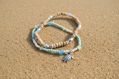 Turtle and beaded bracelet and wooden bracelet with silver beads on sandy background 