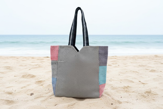 Natural hemp bags with colorful patterns on sand