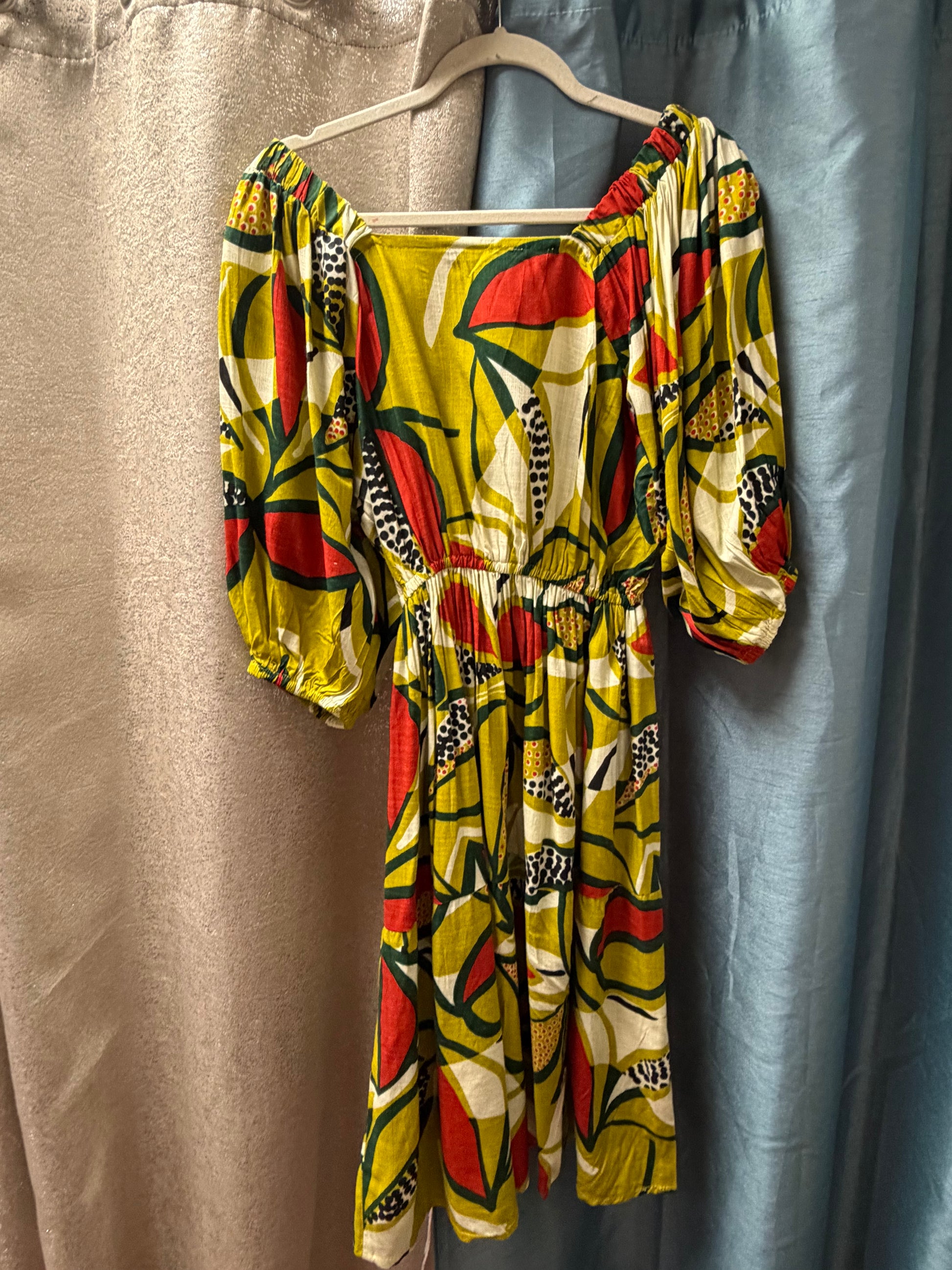 Colorful patterned Avocado Toast Peasant Dress  hanging on a hanger against a plain background