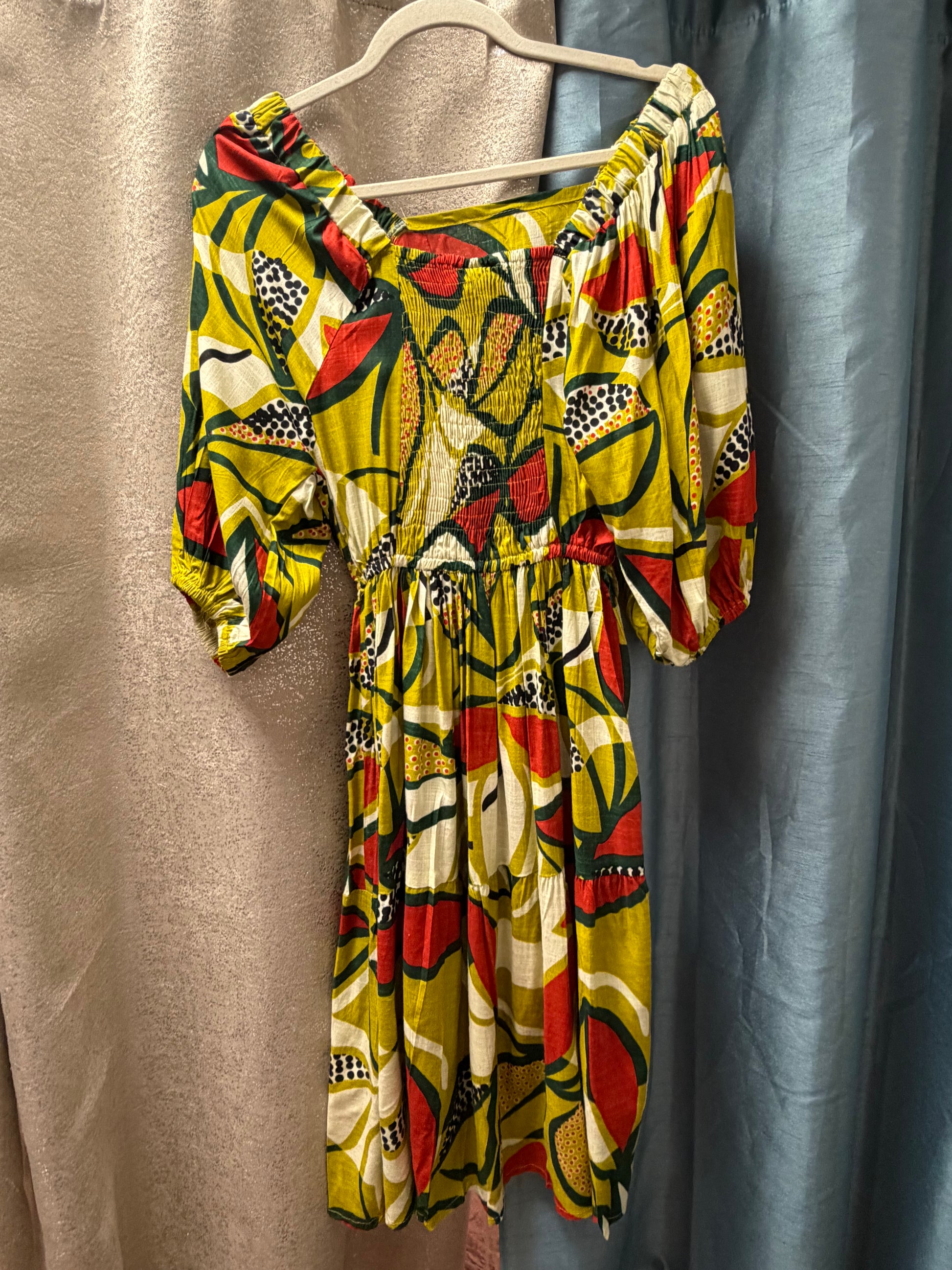 Back view of Avocado Toast Peasant Dress on a hanger against a plain background