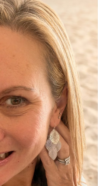 Smiling woman at the beach showing a Silver-Tone Filigree Layered Leaf Dangle Earring, the layered leaf design up close