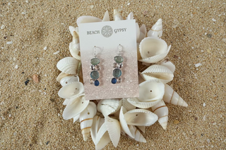 Earrings on a 'Beach Gypsy' branded card surrounded by seashells.