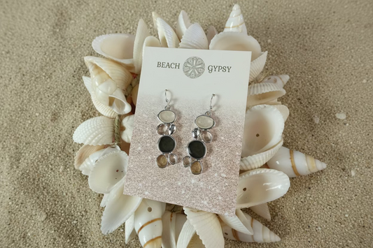 Pair of silver earrings on a 'Beach Gypsy' branded card with seashells in the background.