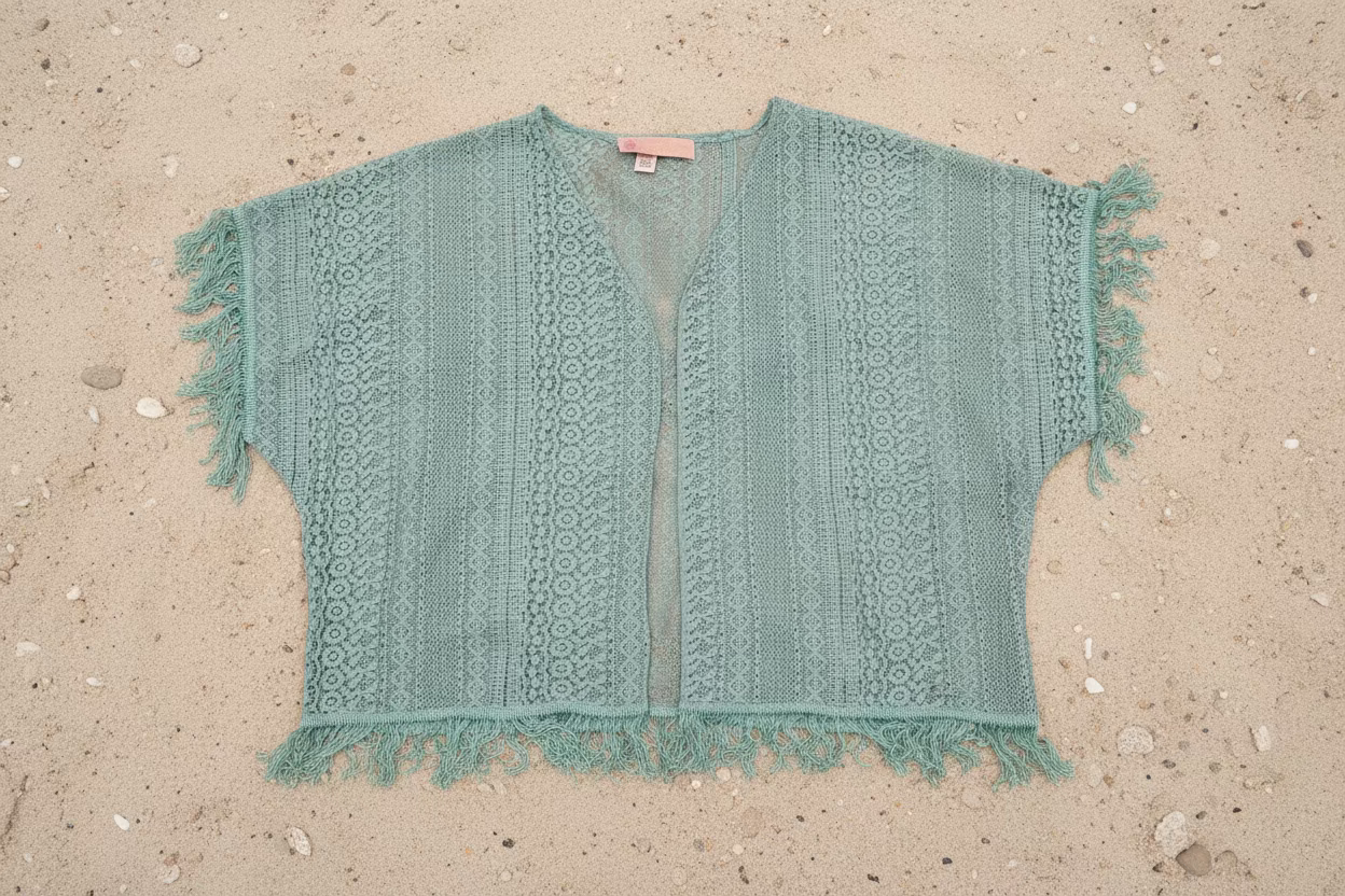Turquoise colored lace kimono with frayed edges on a wooden floor