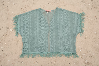 Turquoise colored lace kimono with frayed edges on a wooden floor