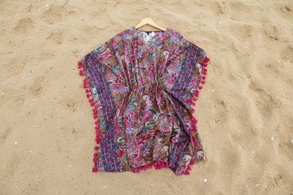 Colorful patterned poncho with tassels on a wooden surface