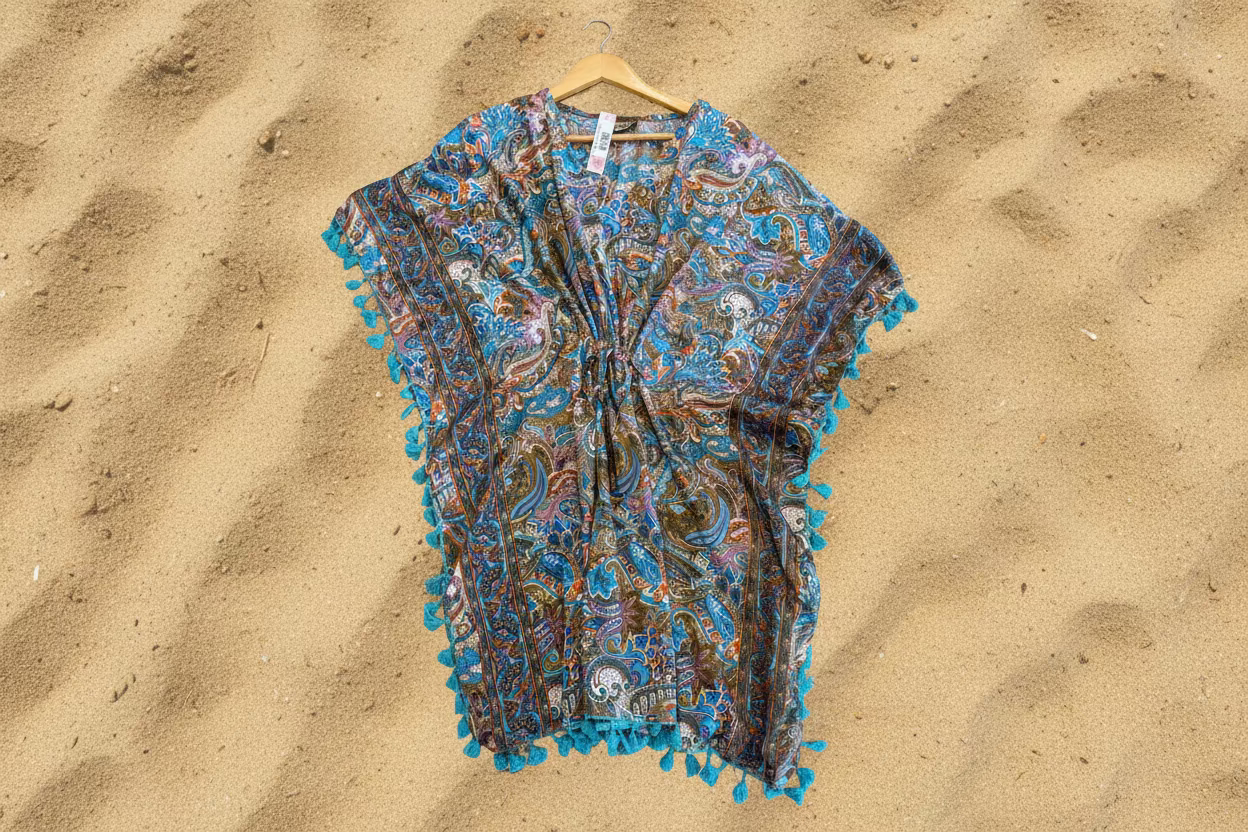Patterned poncho cover-up tunic top with blue tassels on a wooden surface