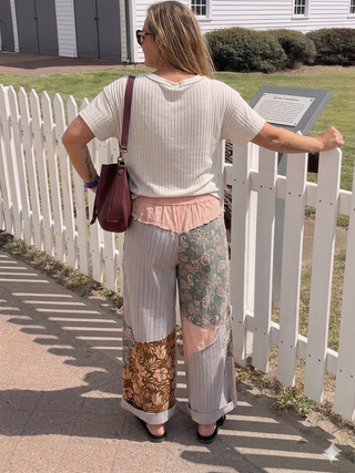 Woman standing by a white picket fence with a house in the background