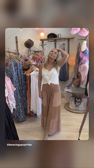 woman wearing chocolate colored patch  flowy pants and white top