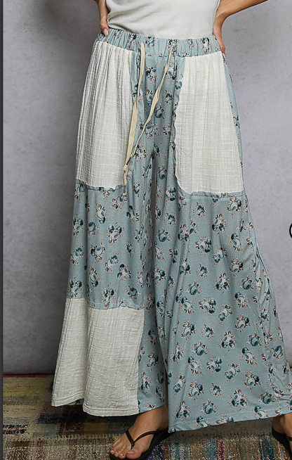 Woman wearing blue floral flowing pants with cream patches 