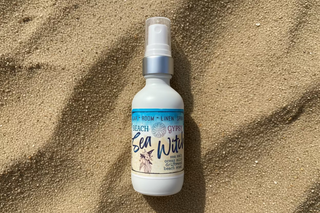 Glass bottle of room spray Sea Witch in sand surface