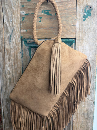 Back of tan sueded fringe wristlet bag showing long tassel zipper pull, fringe trim and braided handle