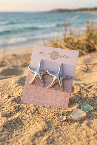 Large Silver Starfish Stud Earrings on a Beach Gypsy earring card, set in the sand by the ocean with sea glass and shells