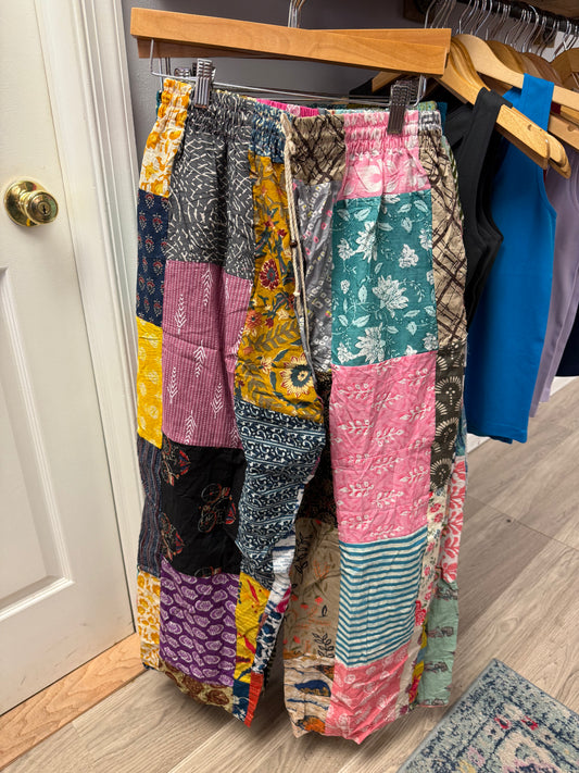 Colorful patchwork pants hanging on a rack against a door.